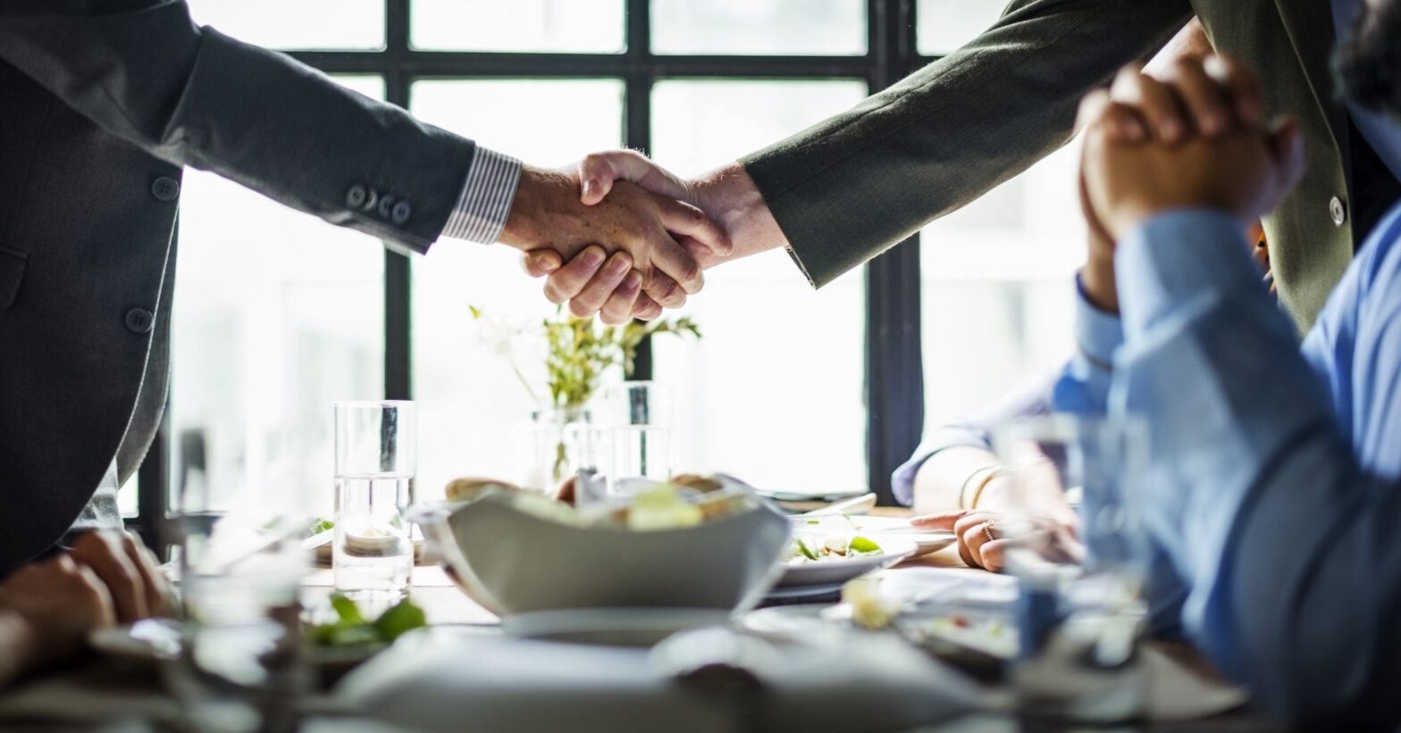 Business deal handshake in over a table in a restaurant
