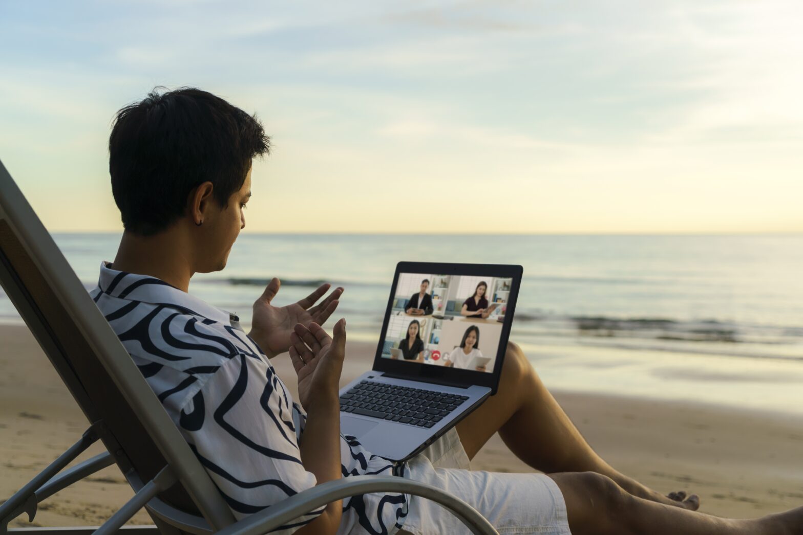 Mixing business and leisure with a bleisure trip working from the beach on laptop